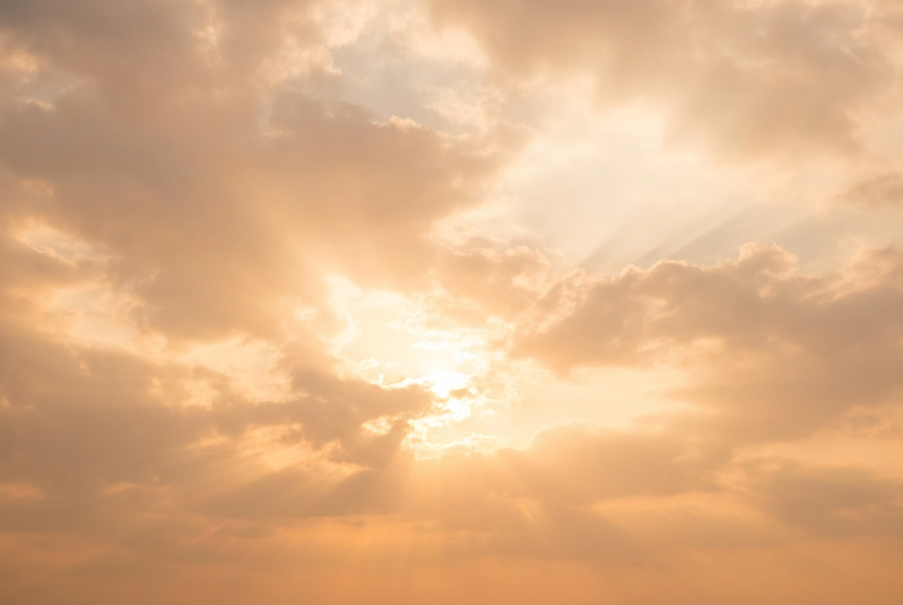 Warm golden sunlight streaming through scattered clouds, captured looking up